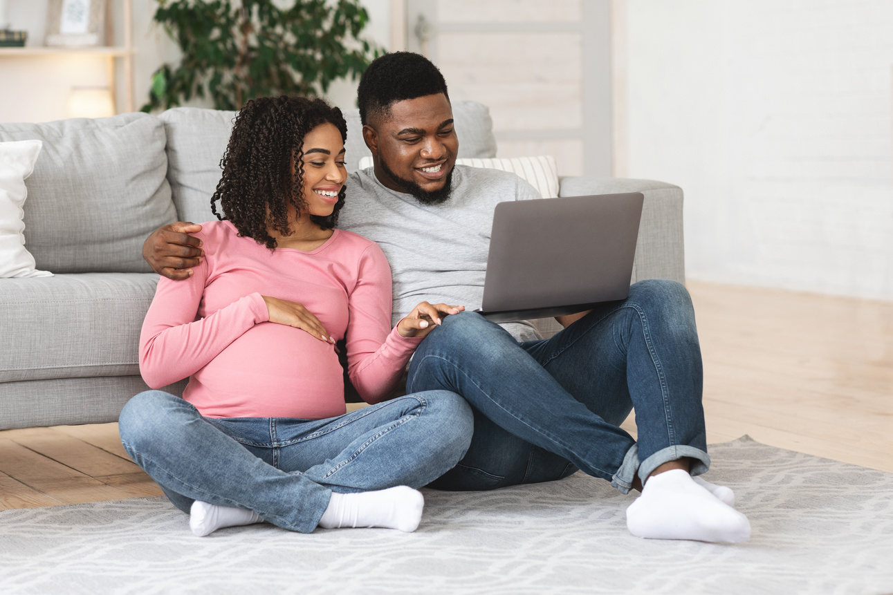 Relaxed pregnant couple using laptop at home