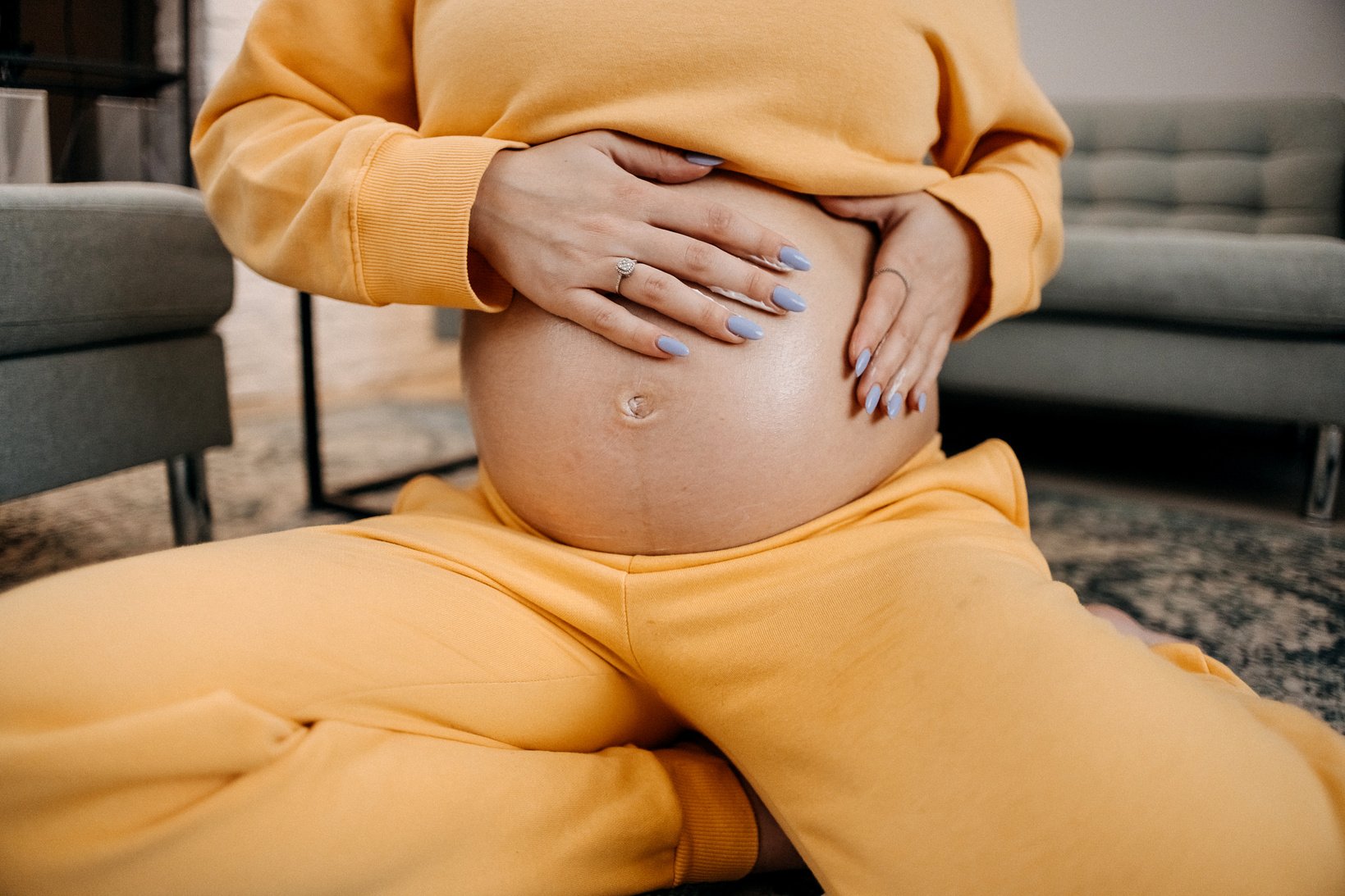 Pregnant woman skin care moisturizer cream on belly.